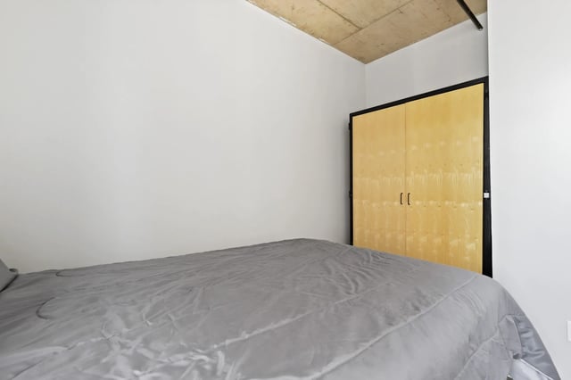 Bed with gray comforter and wooden closet bedroom at Auraria Student Loft in Denver Student Accommodation