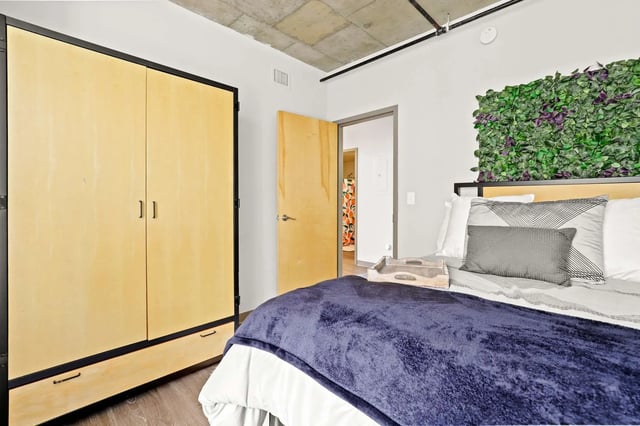 Closet bed pillows tray green accent wall bedroom at Auraria Student Loft in Denver Student Accommodation