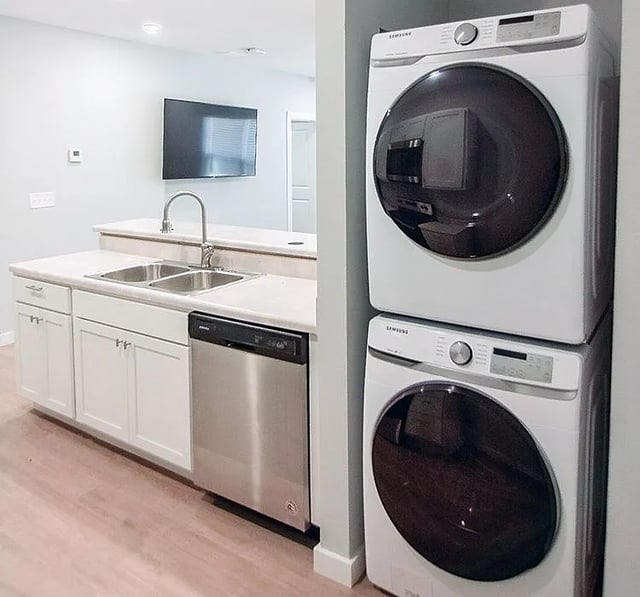 Stacked washer dryer with kitchen and TV. at Rhelm in Pensacola Student Accommodation