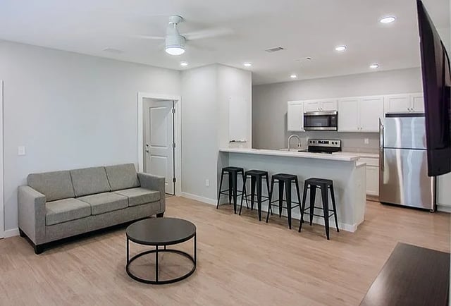 Sofa coffee table kitchen island bar stools kitchen living area at Rhelm in Pensacola Student Accommodation