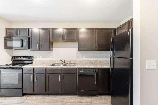 Dark cabinets microwave oven stove dishwasher refrigerator kitchen at Goodnight Commons in Austin Student Accommodation