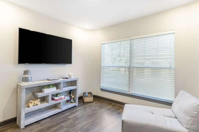 Wall mounted TV shelf with decor and windows living room at Goodnight Commons in Austin Student Accommodation