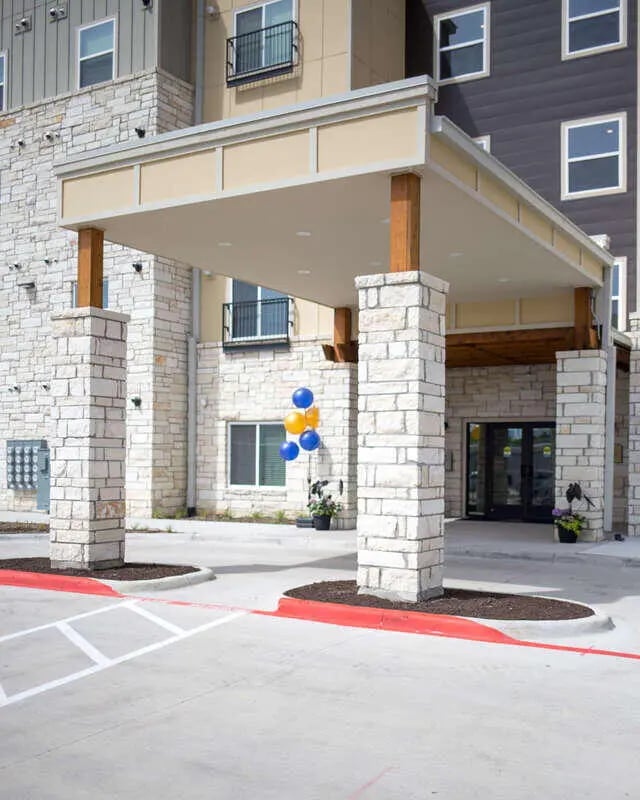 Building entrance with stone columns and balloons exterior at Goodnight Commons in Austin Student Accommodation