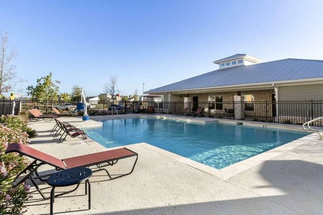 Pool with lounge chairs and building exterior at Goodnight Commons in Austin Student Accommodation