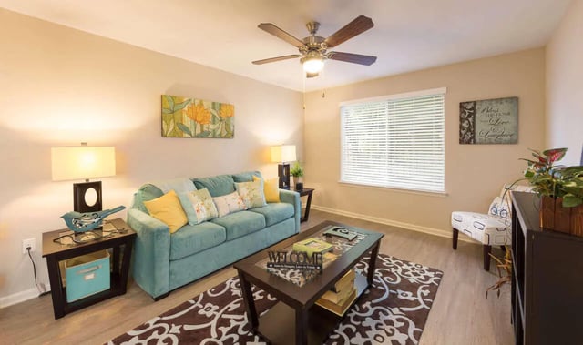 Turquoise sofa coffee table artwork ceiling fan living room at Harris Branch Senior in Austin Student Accommodation