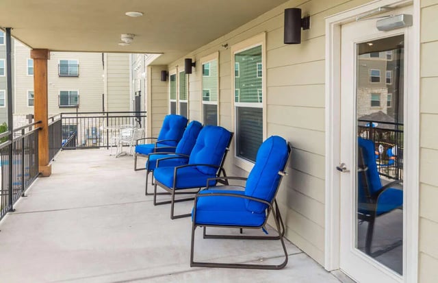 Four blue chairs on concrete patio exterior at Harris Branch Senior in Austin Student Accommodation