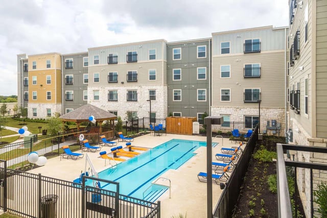 Apartment building pool with lounge chairs exterior at Harris Branch Senior in Austin Student Accommodation