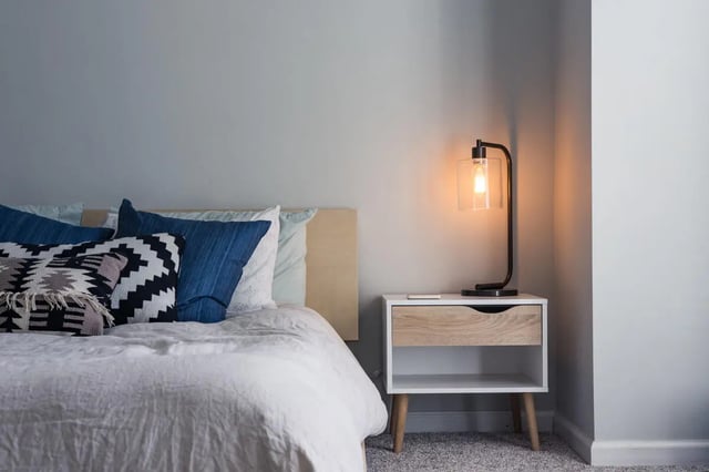 Bed with blue pillows and bedside table bedroom at Ironhorse Flats in Austin Student Accommodation