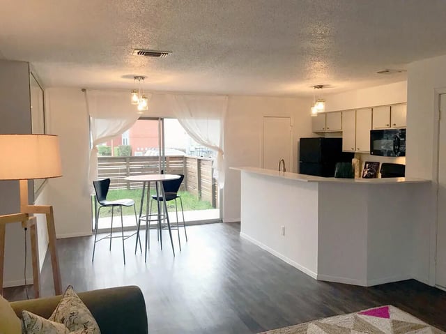 Table chairs kitchen counter and refrigerator living room at Ironhorse Flats in Austin Student Accommodation