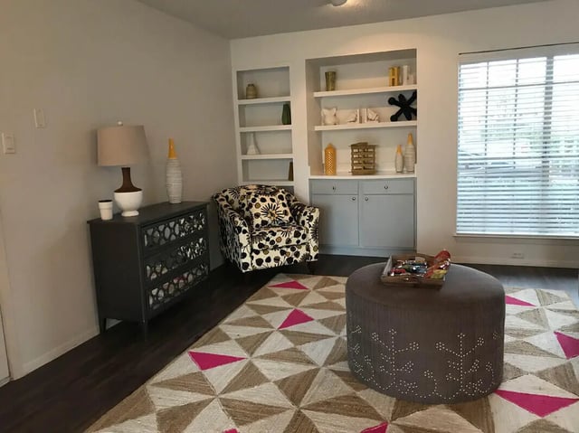 Armchair dresser shelves ottoman rug living room at Ironhorse Flats in Austin Student Accommodation