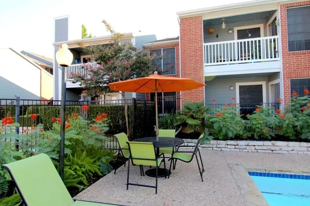 Outdoor seating with umbrella and pool Exterior at Ironhorse Flats in Austin Student Accommodation