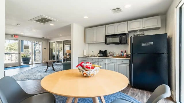 Kitchen area with dining table and black refrigerator kitchen at Ironhorse Flats in Austin Student Accommodation