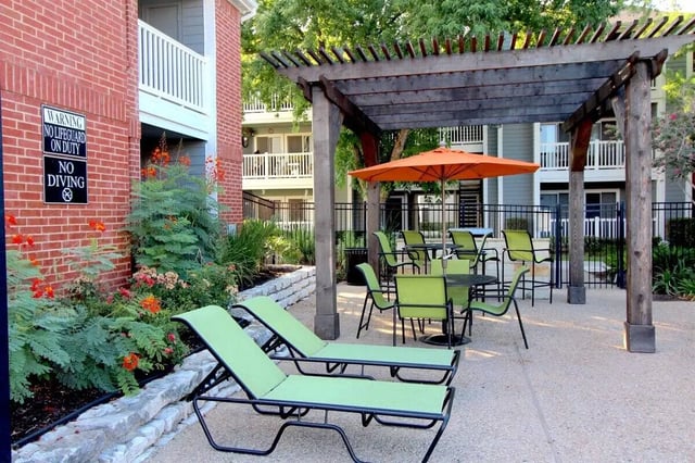 Green lounge chairs and tables under pergola exterior at Ironhorse Flats in Austin Student Accommodation