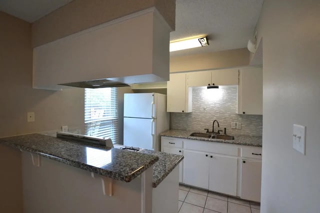 Granite counter white cabinets refrigerator sink kitchen at Lightsey Place Apartments in Austin Student Accommodation