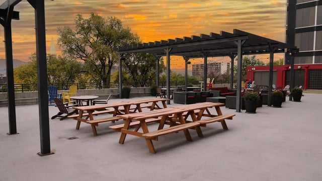 Picnic tables under a pergola on rooftop exterior at Vista in Denver Student Accommodation