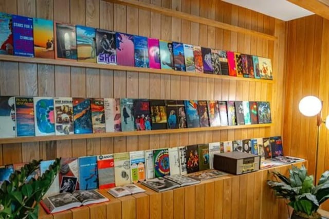 Records and books on wooden shelves communal area at Rambler Austin in Austin Student Accommodation