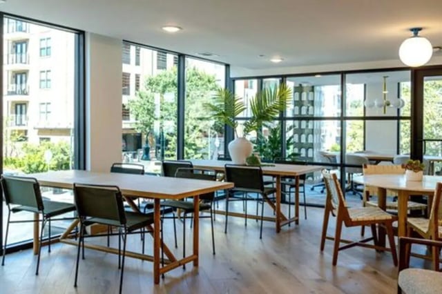 Tables and chairs with plant in spacious common area at Rambler Austin in Austin Student Accommodation