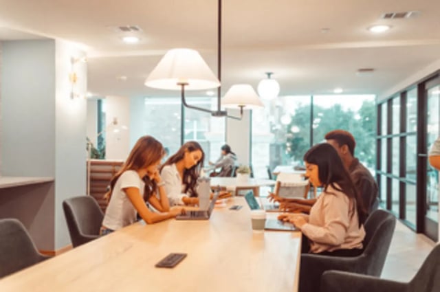 Students working on laptops at a communal table study area at Rambler Austin in Austin Student Accommodation