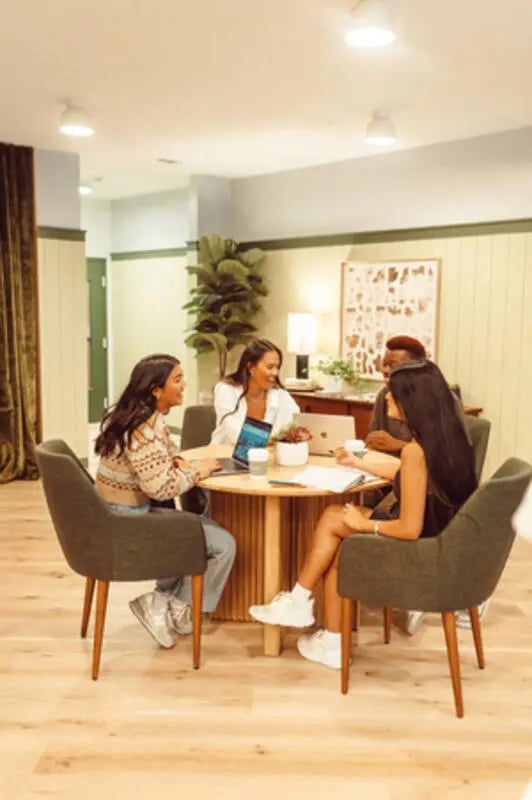 Students working around a round table communal area at Rambler Austin in Austin Student Accommodation