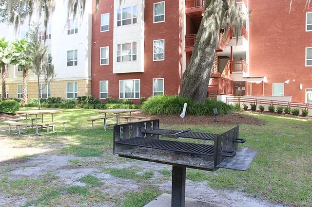 Grill picnic tables and apartment building exterior exterior at The Continuum in Gainesville Student Accommodation