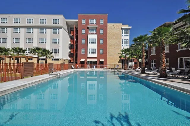Apartment buildings surround a large swimming pool exterior at The Continuum in Gainesville Student Accommodation