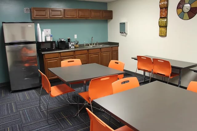 Kitchenette with refrigerator microwave sink and tables. at The Continuum in Gainesville Student Accommodation