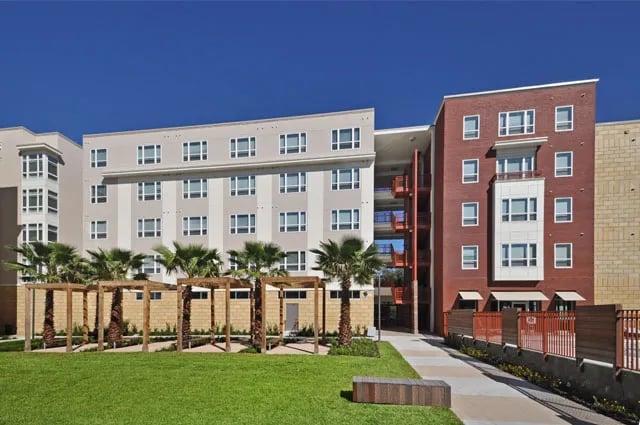 Modern apartment building with palm trees and seating exterior at The Continuum in Gainesville Student Accommodation