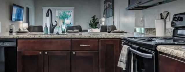 Dark wood cabinets granite countertops sink and stove kitchen at Regency Gardens in Bryan Student Accommodation