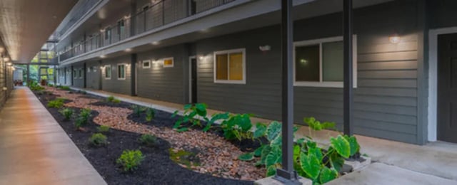 Exterior walkway with landscaping and building facade at Regency Gardens in Bryan Student Accommodation