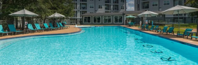 Turquoise lounge chairs under umbrellas pool area at Regency Gardens in Bryan Student Accommodation