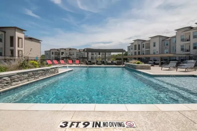 Swimming pool with lounge chairs exterior at Riverside Villas in Fort Worth Student Accommodation