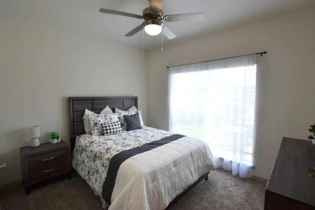 Bed with patterned bedding and ceiling fan bedroom at Riverside Villas in Fort Worth Student Accommodation