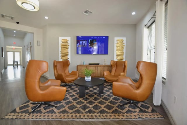 Four brown chairs around table and TV living room at Riverside Villas in Fort Worth Student Accommodation