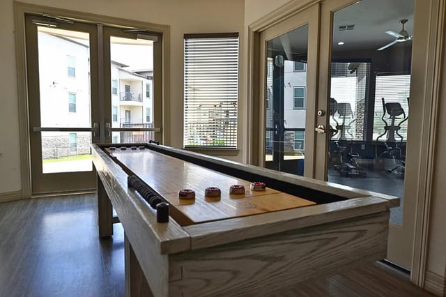 Shuffleboard table with red pucks game room at Riverside Villas in Fort Worth Student Accommodation