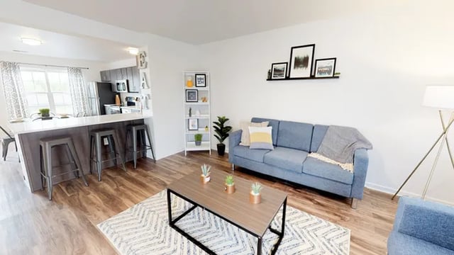 Blue sofa coffee table bar stools kitchen living room at Canvas Townhomes in Allendale Student Accommodation