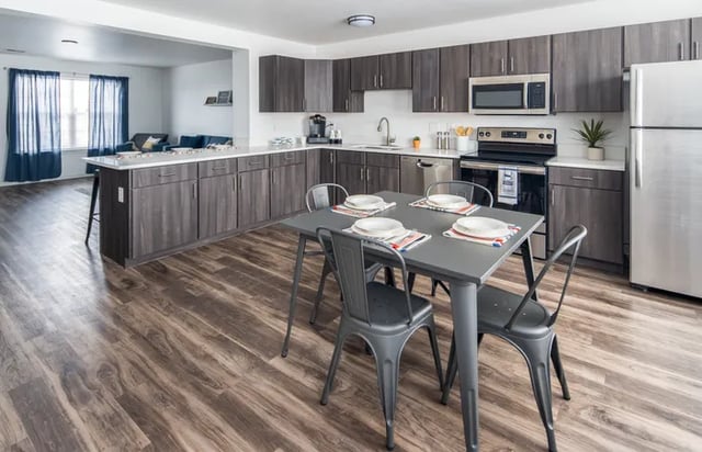 Table chairs cabinets refrigerator and appliances kitchen at Canvas Townhomes in Allendale Student Accommodation