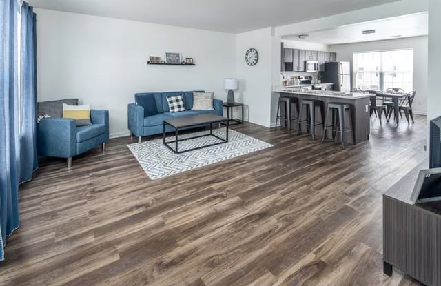 Blue sofa armchair coffee table open kitchen living room at Canvas Townhomes in Allendale Student Accommodation