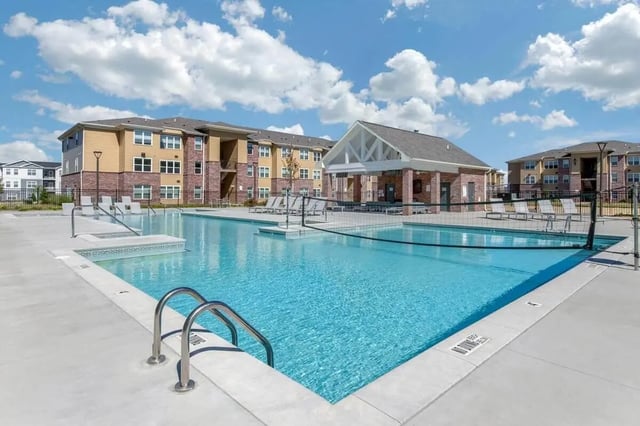 Blue swimming pool with lounge chairs volleyball net exterior at Locale Student Housing in Allendale Student Accommodation
