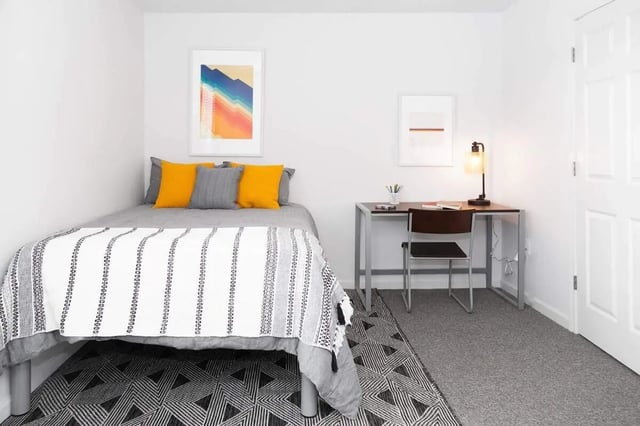 Bed with yellow pillows desk chair lamp bedroom at Locale Student Housing in Allendale Student Accommodation