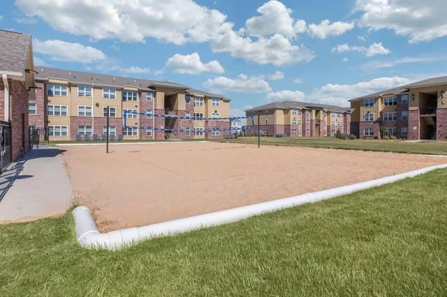 Sand volleyball court with apartment buildings exterior at Locale Student Housing in Allendale Student Accommodation