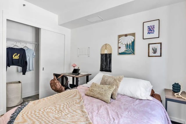 Bed with patterned throw desk with laptop and closet Bedroom at Ace Berkeley in Berkeley Student Accommodation