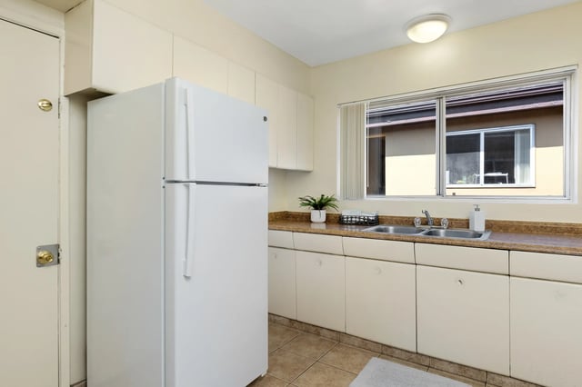 White refrigerator sink counter cabinets window kitchen at College Campanile in San Diego Student Accommodation