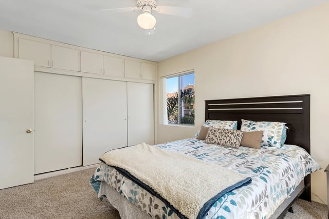 Bed with patterned bedding ceiling fan and closets bedroom at College Campanile in San Diego Student Accommodation