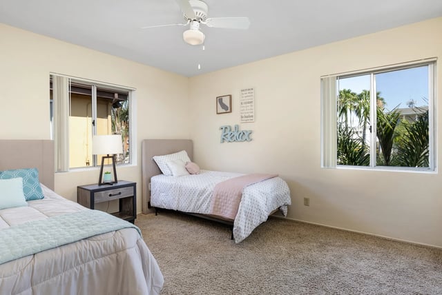 Two beds nightstand lamp ceiling fan bedroom at College Campanile in San Diego Student Accommodation