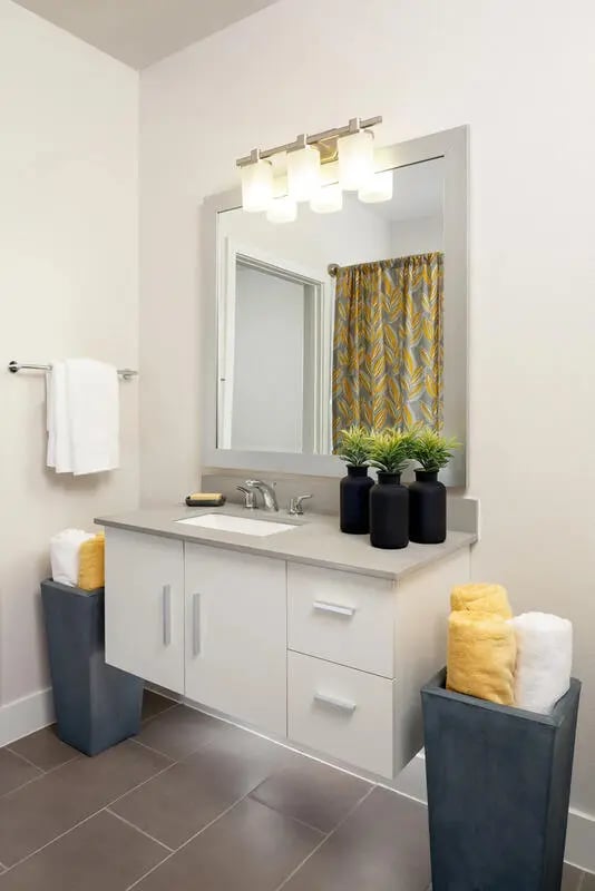 White vanity sink with towels and plants bathroom at The Flats at Big Tex in San Antonio Student Accommodation
