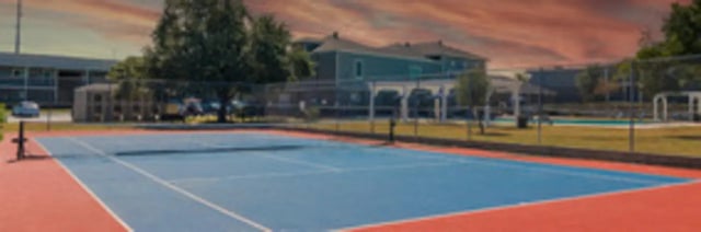 Blue and red tennis court with buildings exterior at The Grand 1501 in College Station Student Accommodation