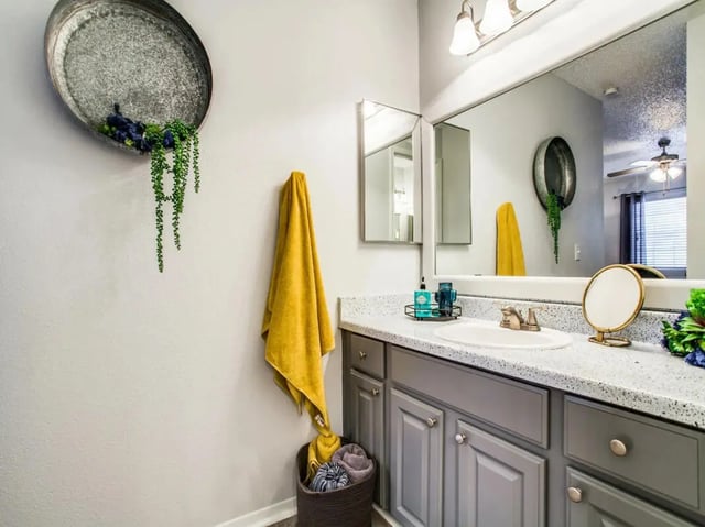Sink vanity with yellow towel and basket bathroom at The Joseph at Huebner in San Antonio Student Accommodation