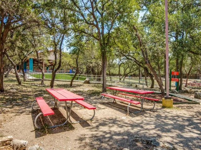 Red picnic tables under trees playing area at The Joseph at Huebner in San Antonio Student Accommodation