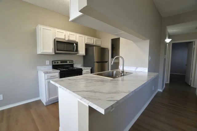 White cabinets stainless steel appliances marble island kitchen at The Oaks of Arlington in Arlington Student Accommodation