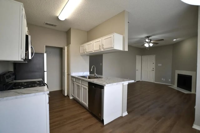 Kitchen with white cabinets dishwasher and living area at The Oaks of Arlington in Arlington Student Accommodation